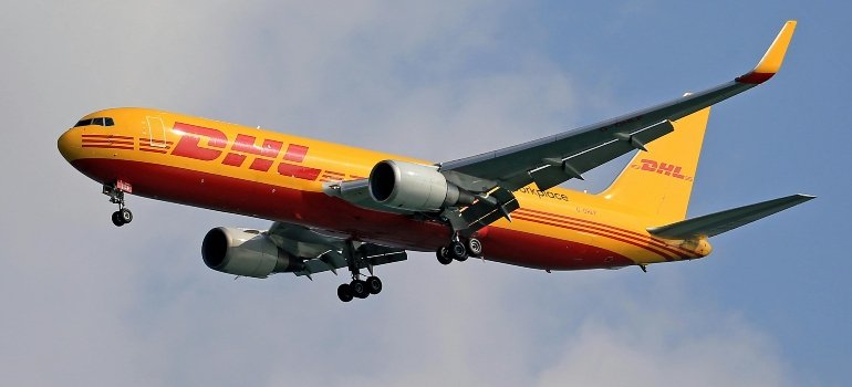 DHL yellow airplane flying in the sky, symbolizing the company’s strong presence and growing opportunities for those moving for a job.