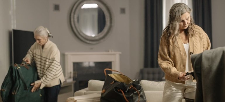 Two women in a cozy living room are packing bags