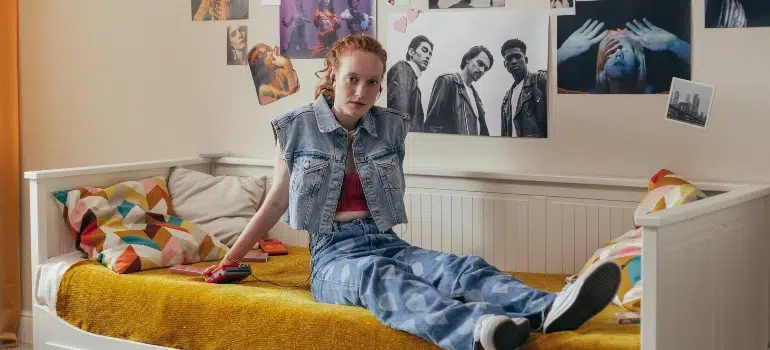 Tips for moving to a new city alone 4 Person settling in after moving to a new city alone, with bed unpacked and posters on the wall