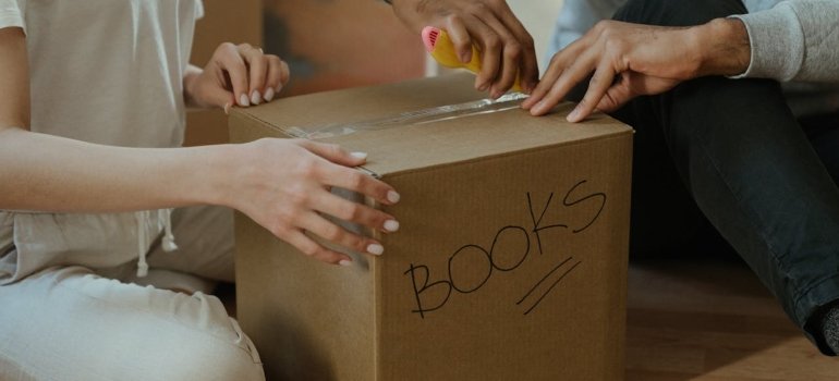 a couple unpacking a box labeled BOOKS, showing how to unpack after moving