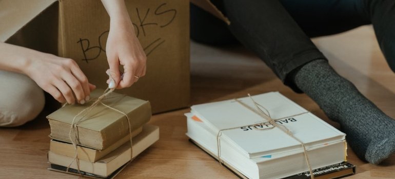 The best way to pack books for moving 2 Couple sorting books beside cardboard moving boxes
