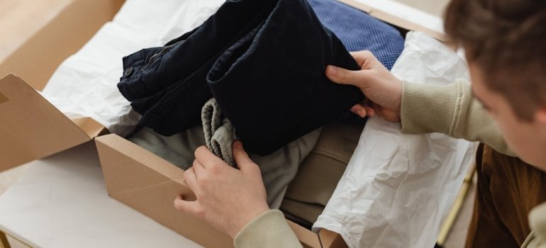 Person unpacking a wardrobe box after using the best way to pack clothes for moving.