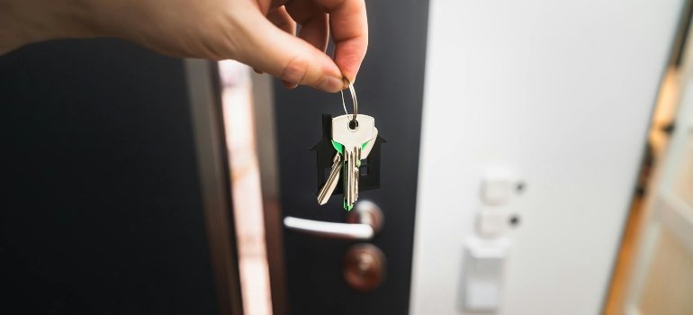 Hand holding a set of keys in front of an open door, symbolizing a move to Blue Ash and the question is Blue Ash a good place to live.