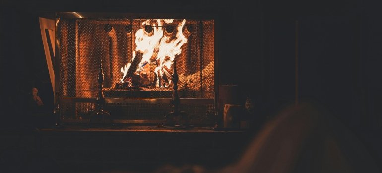 Practical checklist of things you need when moving out 3 Warm fireplace glowing in a peaceful living room during the first night after moving in.