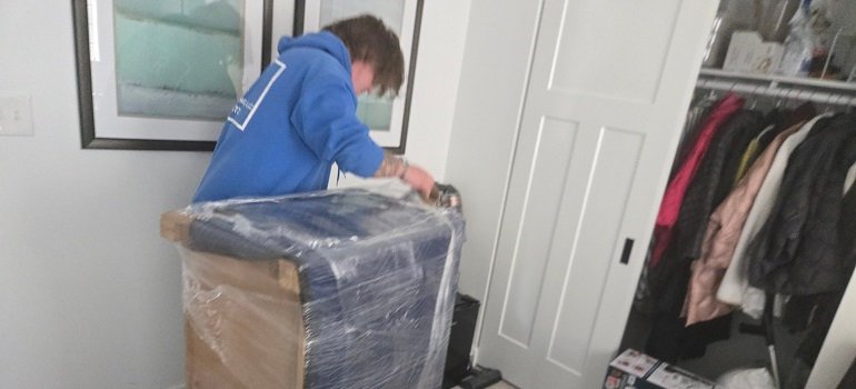 Mover wrapping furniture inside home during winter relocation in Ohio