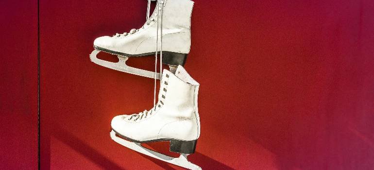 White ice skates hanging on a red wall