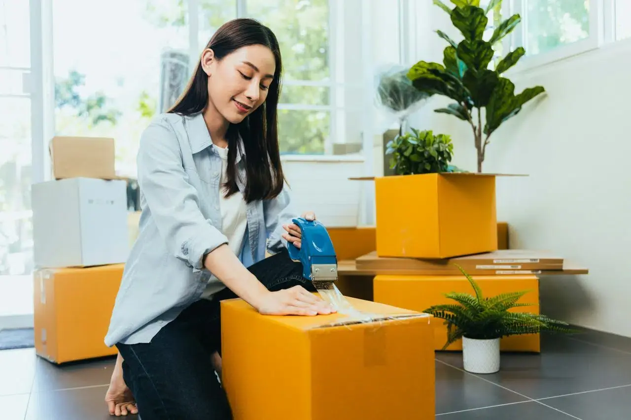 asian woman packing boxes to move new home