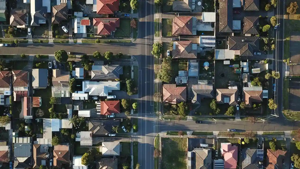 Aerial view of a suburban neighborhood showing rows of houses, green lawns, and quiet residential streets.
