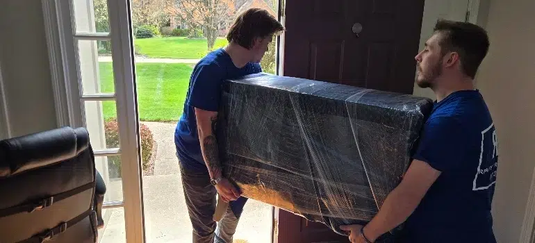 Furniture Movers 2 Two men transporting a large piece of furniture into a house, demonstrating teamwork and careful handling.