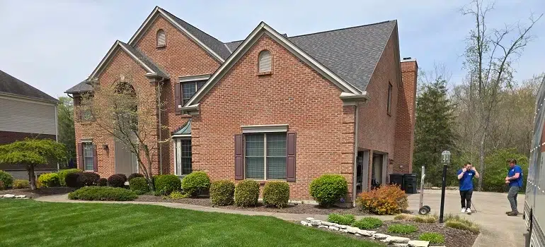 Spacious brick house with movers preparing front yard