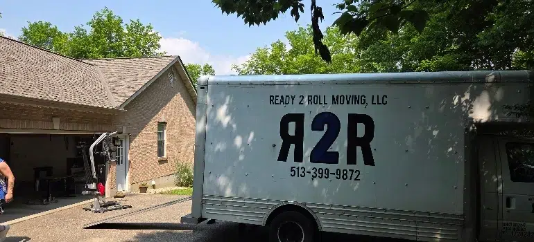 Commercial Movers 2 A moving truck labeled "Ready 2 Roll Moving, LLC" parked in front of a house, with trees and a clear sky in the background.