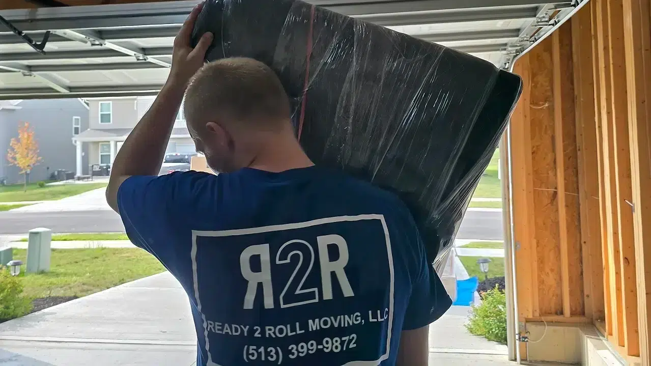 Mover carrying wrapped sofa, ready to move modular furniture