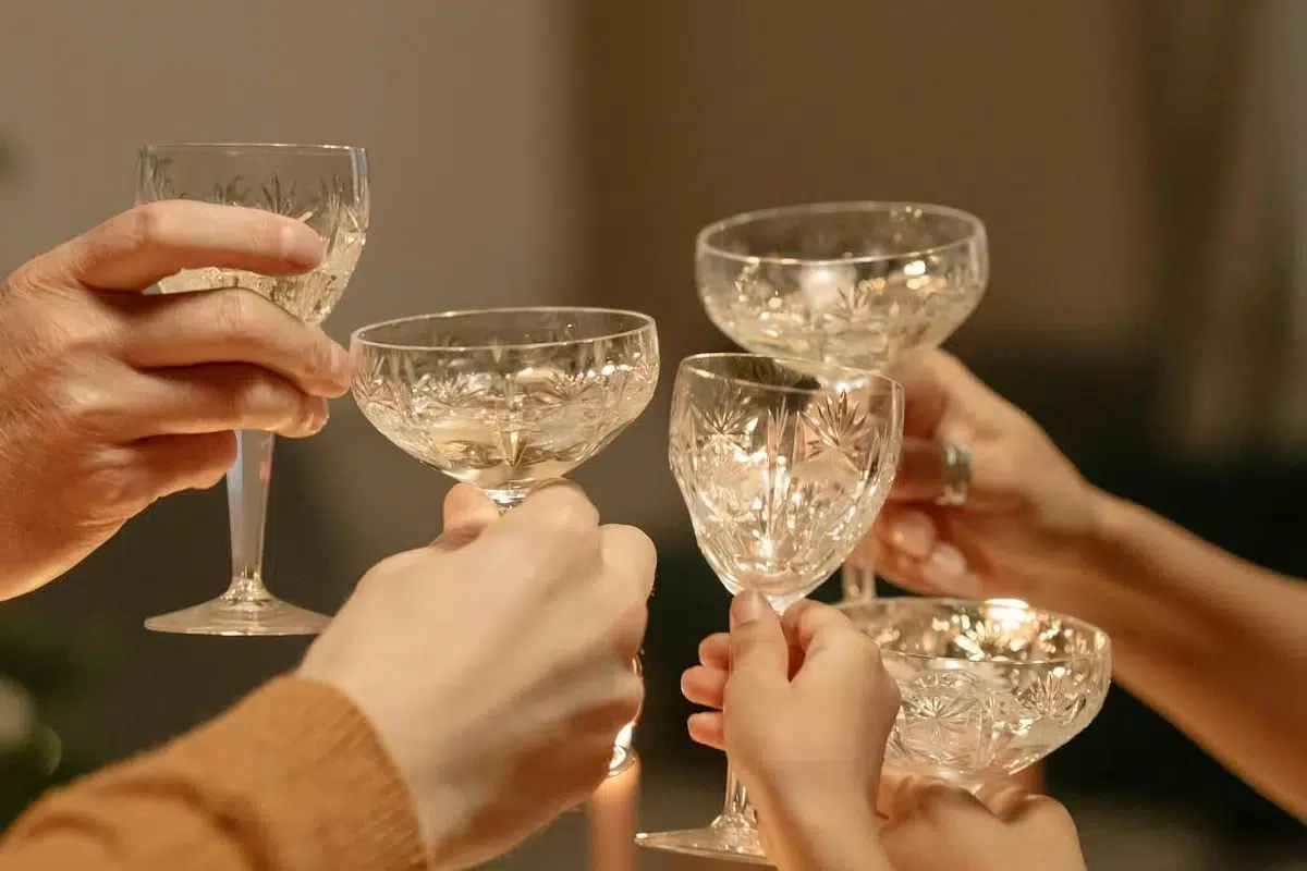 Several hands clink elegant crystal champagne glasses