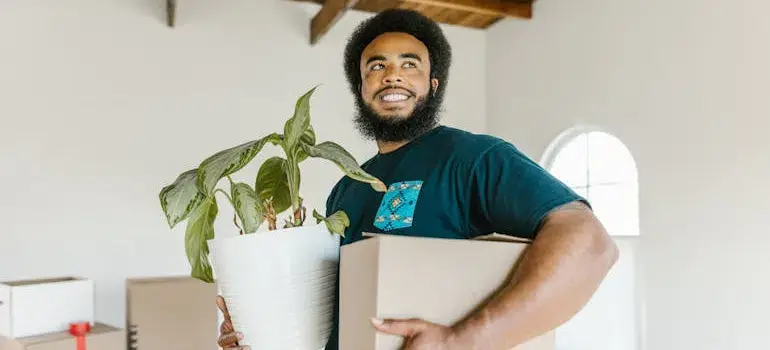 Your Guide to Moving to Loveland Ohio 2 a mover holding a box and a flower pot