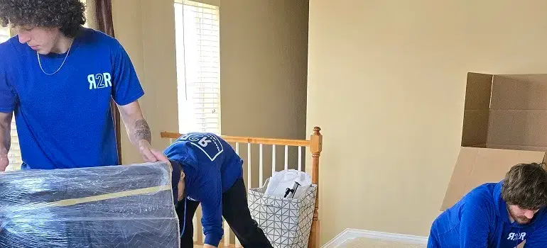 Professional movers wrapping furniture in an upstairs hallway.