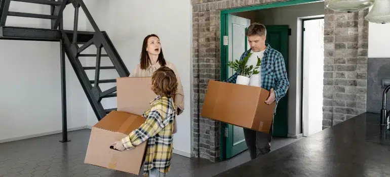 Cincinnati Apartment vs House Moves: What’s the Difference? 3 Family carrying moving boxes inside a modern apartment, highlighting challenges in apartment vs house moves.