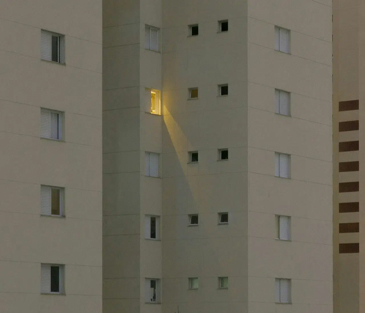 High-rise apartment building exterior with one lit window