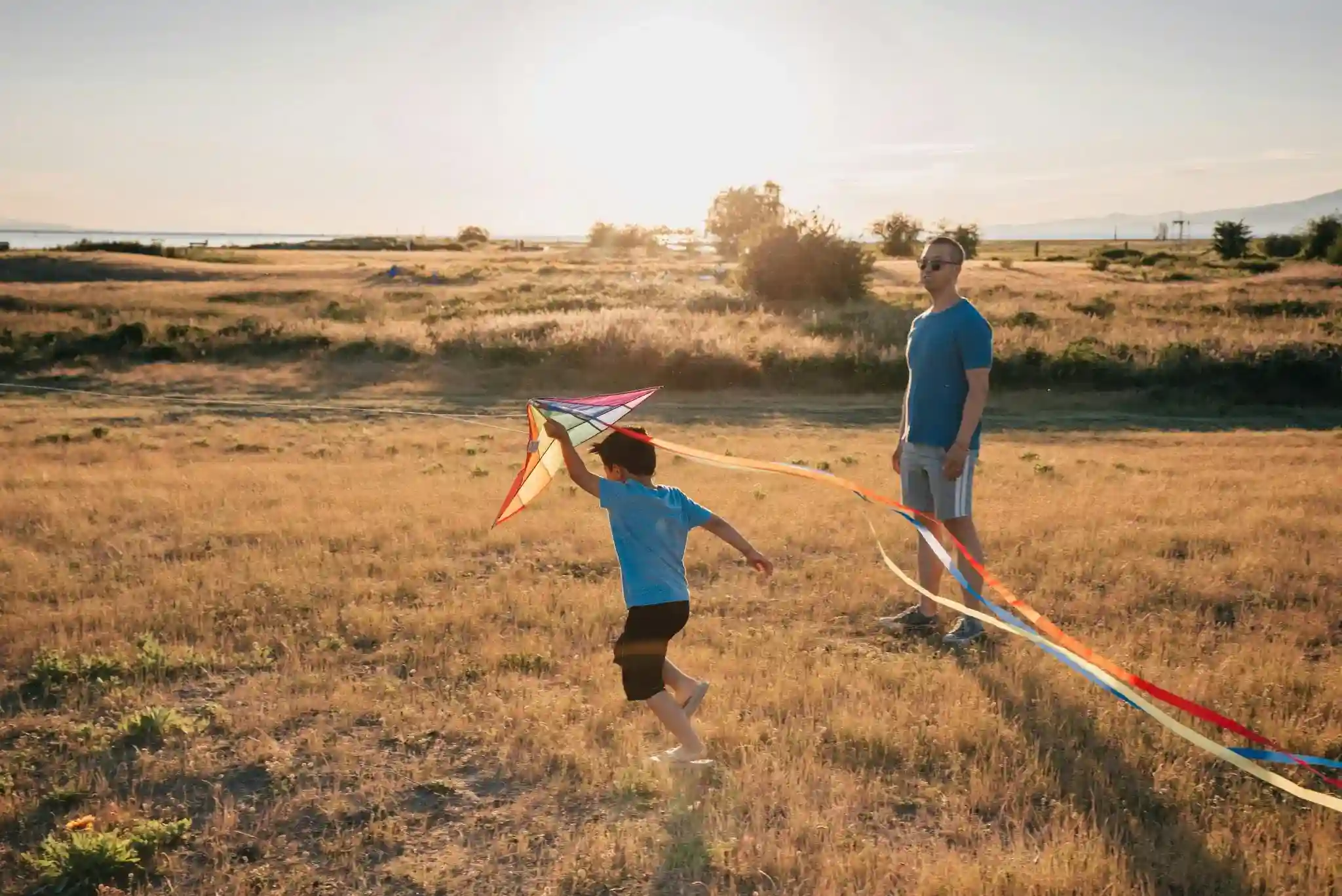 A father and a son playing with a kite.