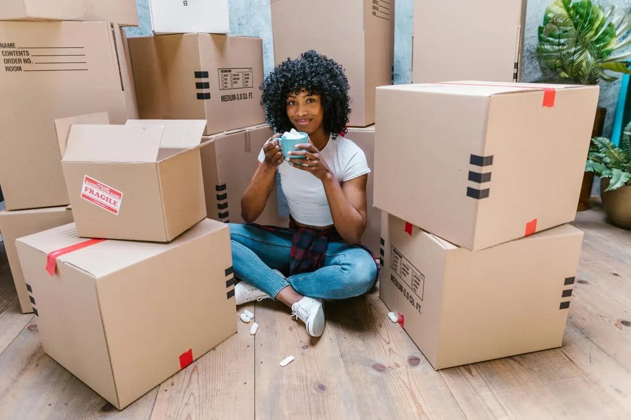 A Woman Holding a Blue Cup while Sitting on the Wooden Floor