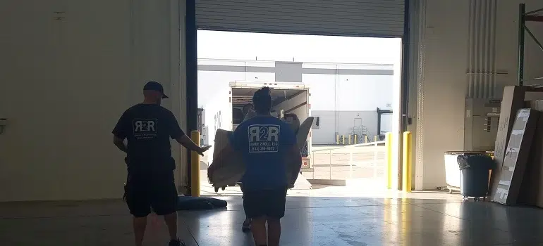 7 reasons to move your Fairfield office during summer 2 Movers carrying furniture through warehouse loading bay